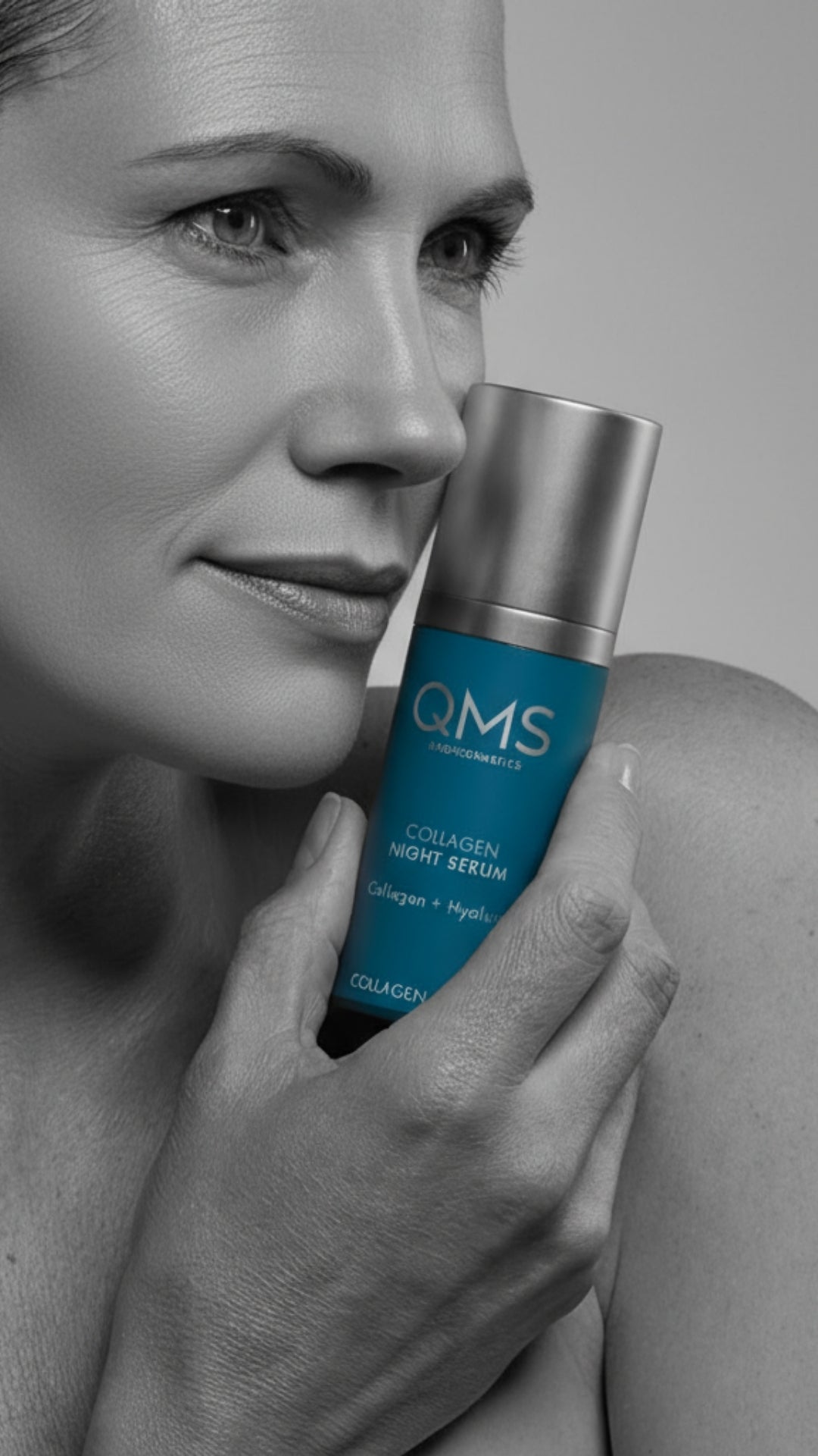 Woman holding a QMS skincare product with a gray background