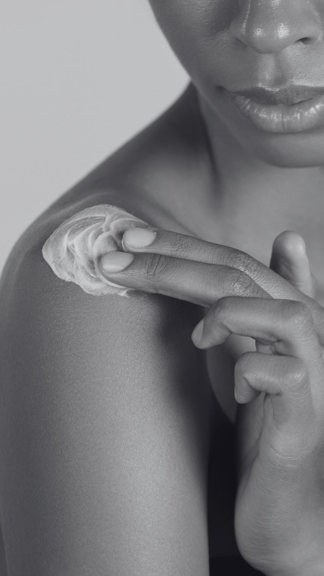 Person applying a small amount of cream or lotion to their shoulder with their finger.